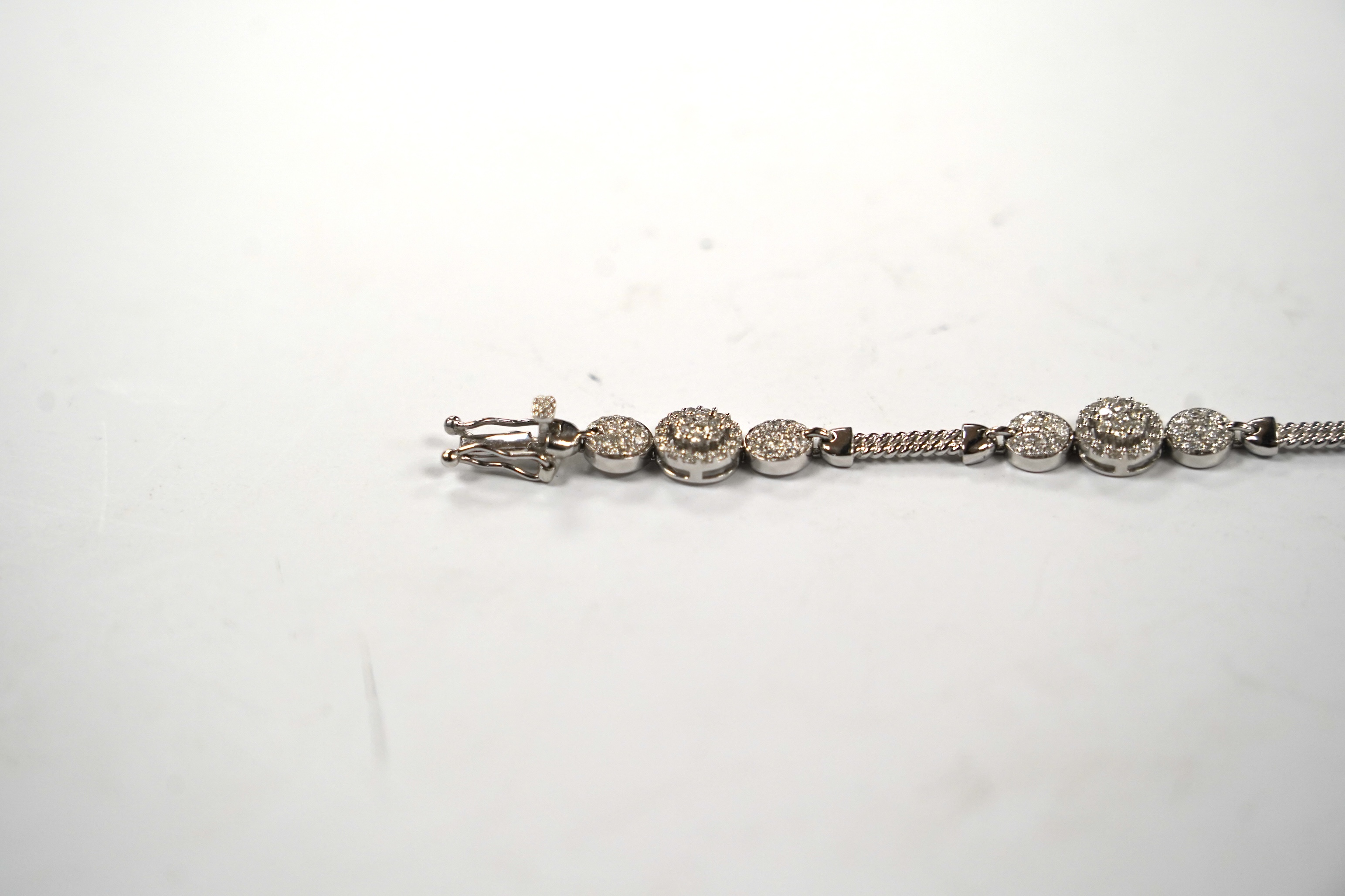 A modern 14k white metal and diamond cluster set line bracelet, the total diamond weight approximately 2.00ct, 16.5cm, gross weight 11.1 grams.